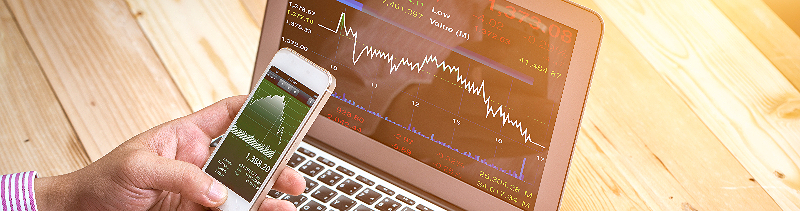 Employee tracking the stock market on their phone and laptop.